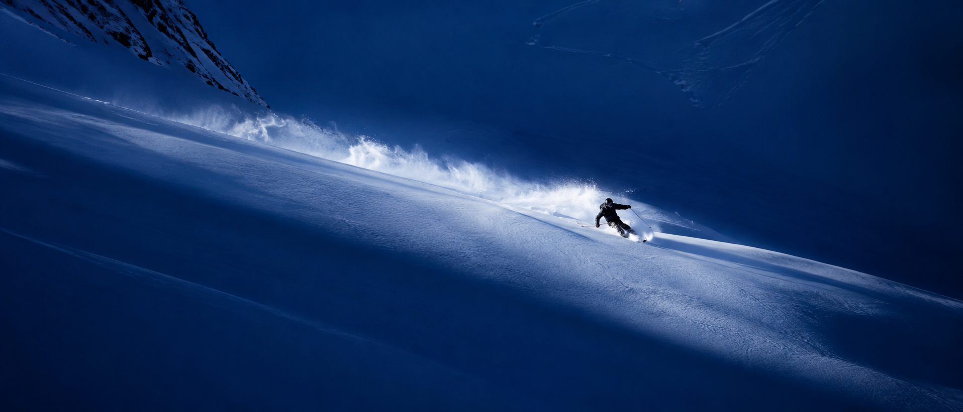 Skier carving a deep powder turn on a steep alpine face