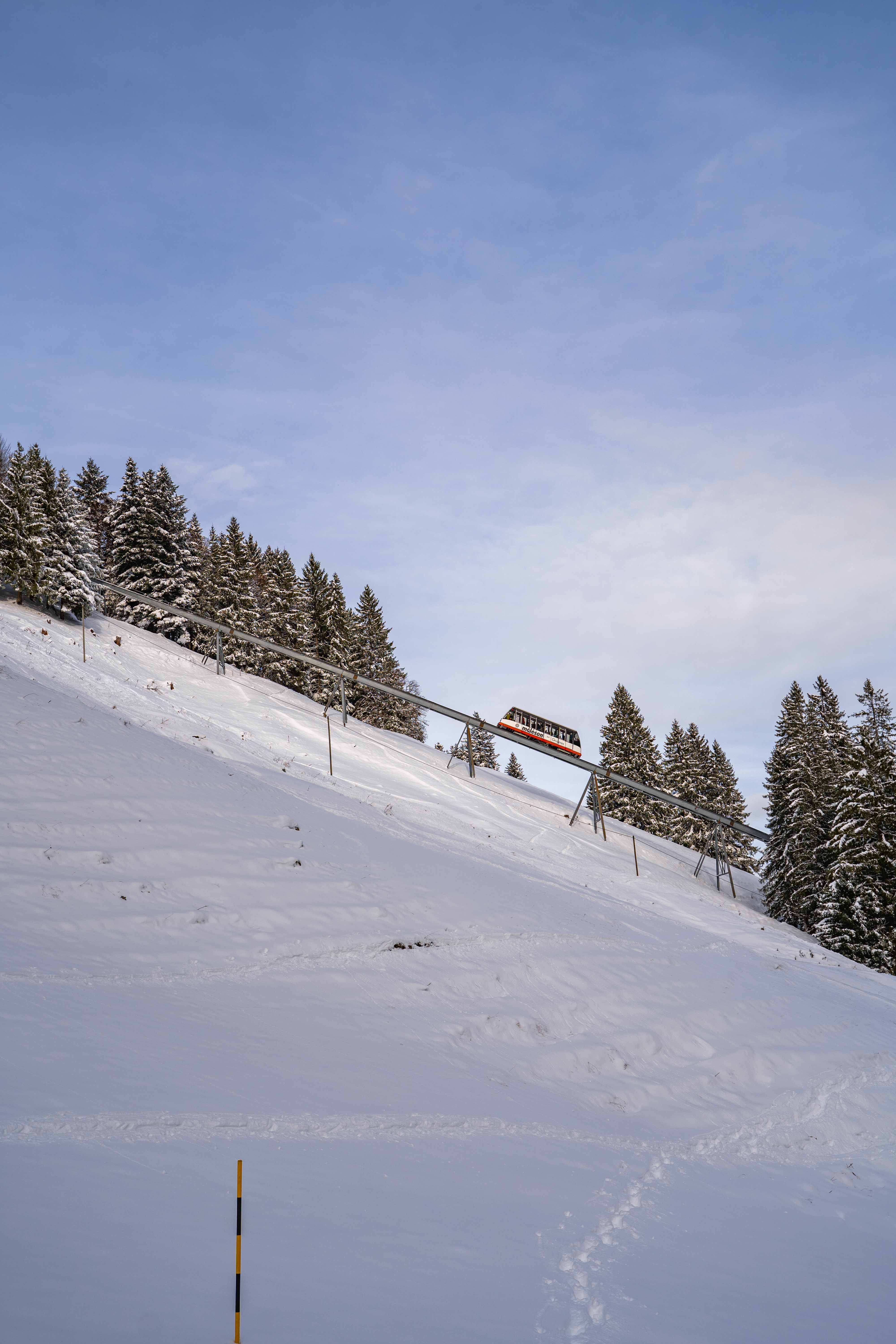 Funicular climbing a snowy slope at Le Moléson