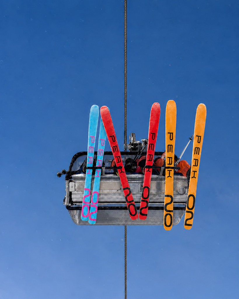 Peak2002 skis hanging from a chairlift against a clear blue sky