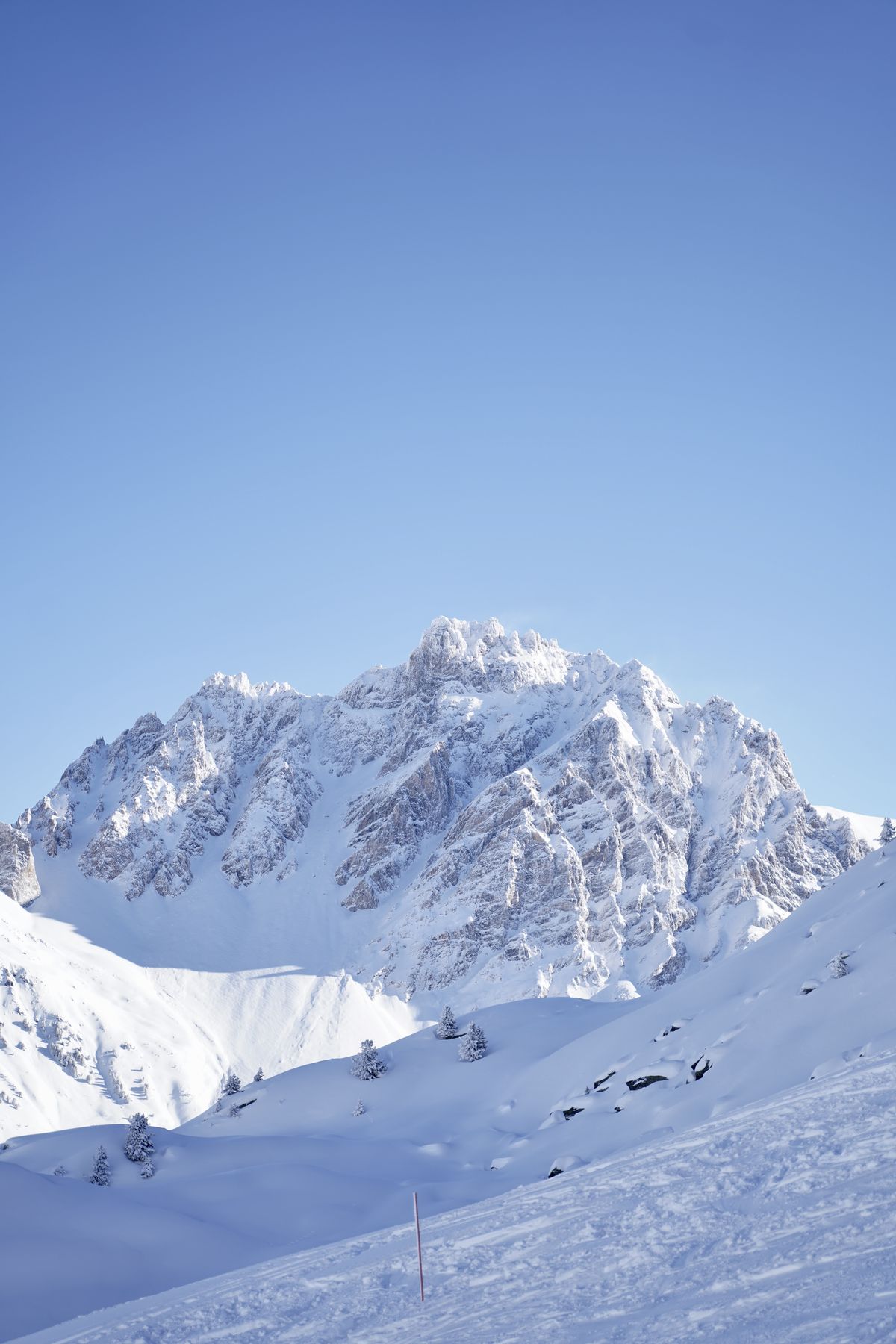 Snow-covered alpine face under a clear blue sky