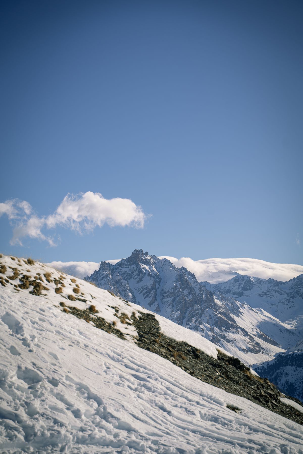 Ski tracks on a slope with a distant peak in cloud