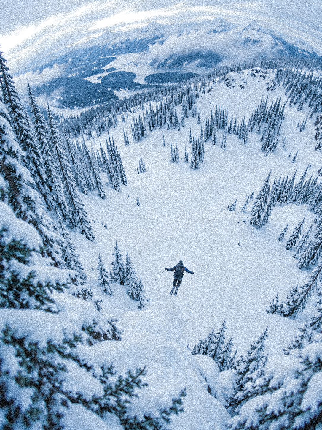 Skier dropping into a snow-covered alpine bowl