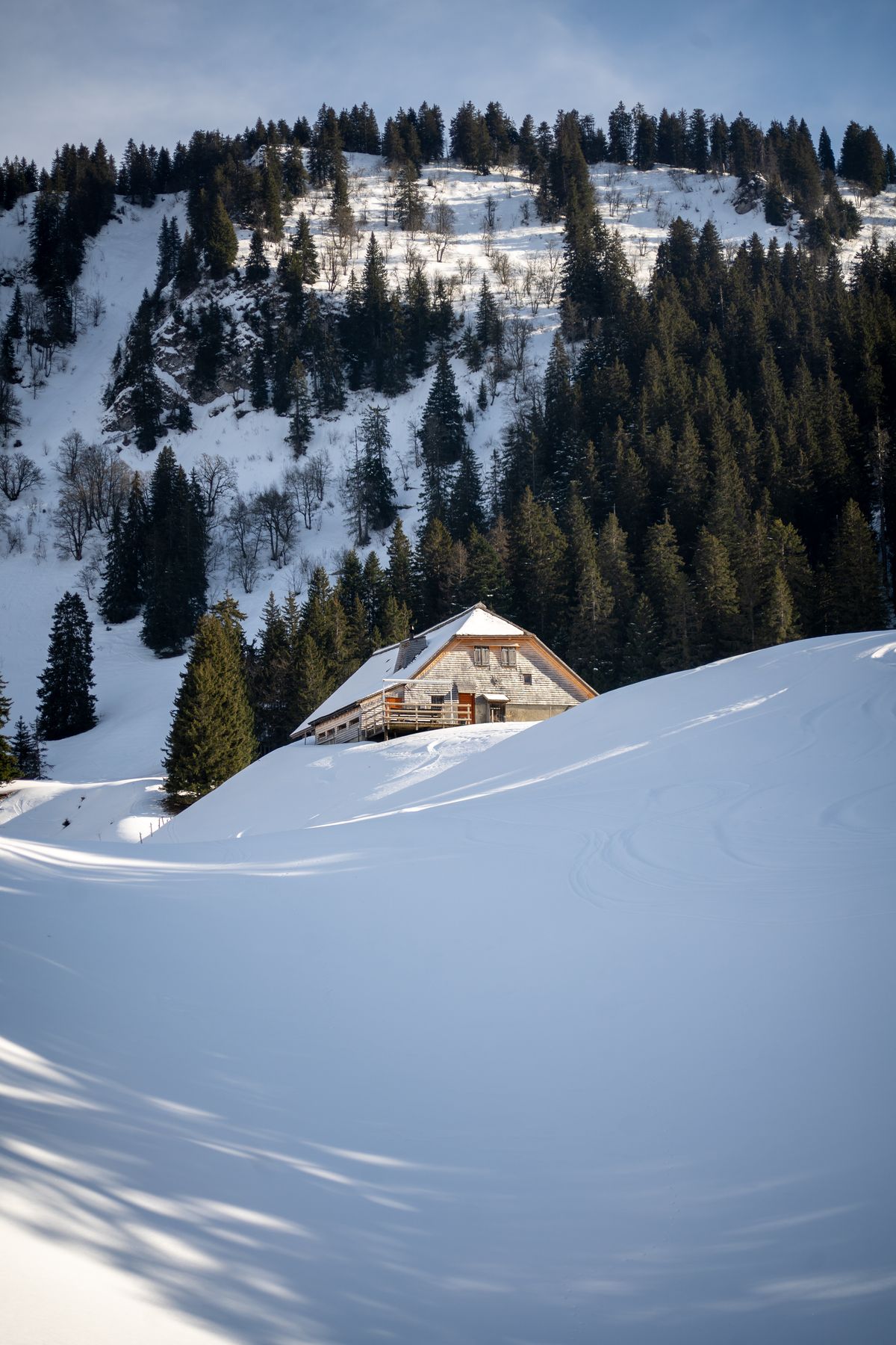 Wooden chalet in deep snow under Le Molard